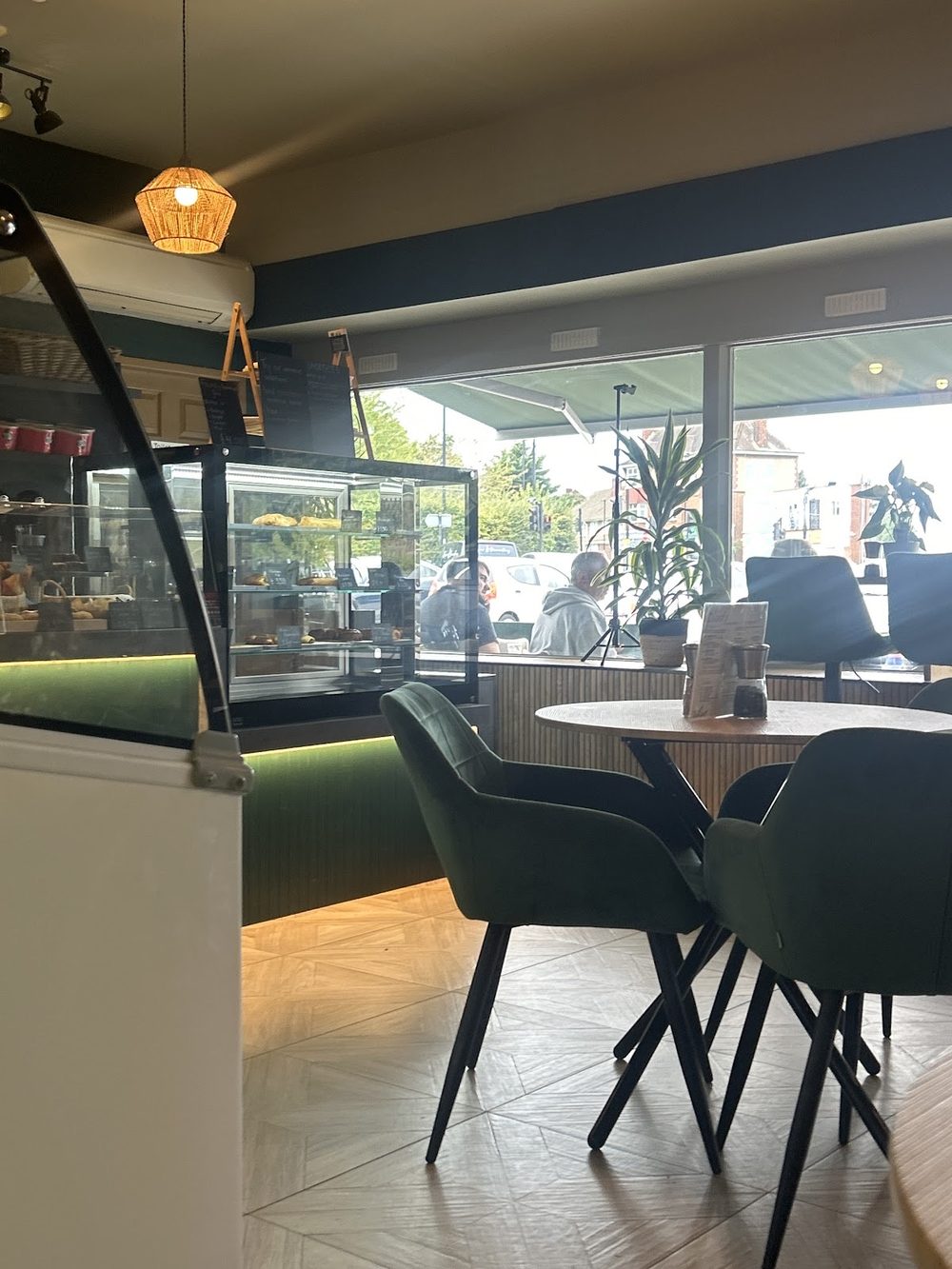 Inside Blends & Beyond, looking past the counter and a pendant light to the front window, with dark chairs and a wooden table.