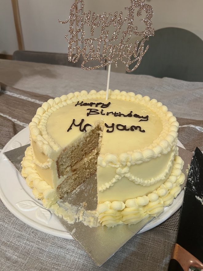 A cut birthday cake with white buttercream.
