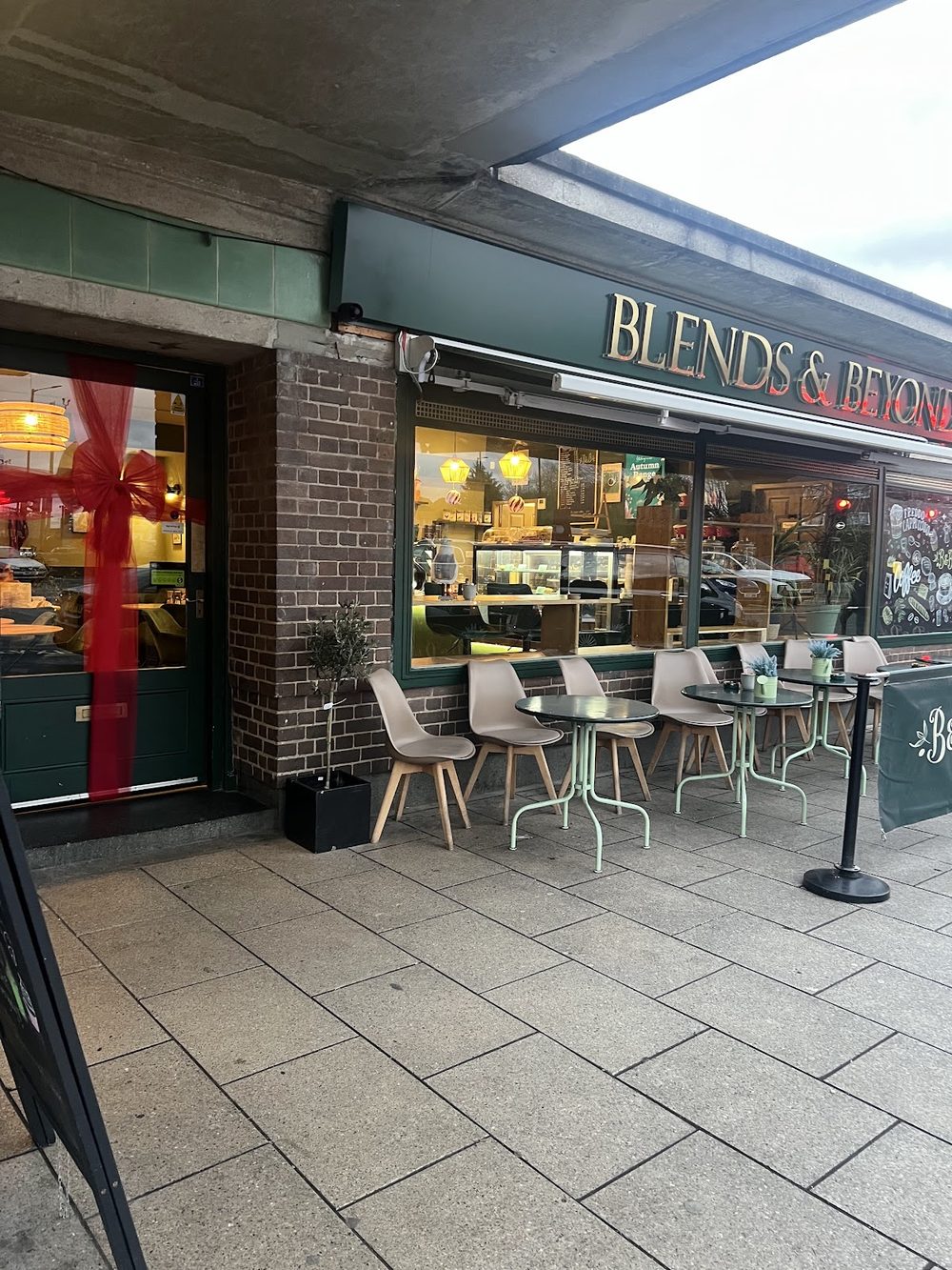 The Blends & Beyond shopfront on the pavement at Oakwood Station, with outdoor stools and tables under a green fascia.