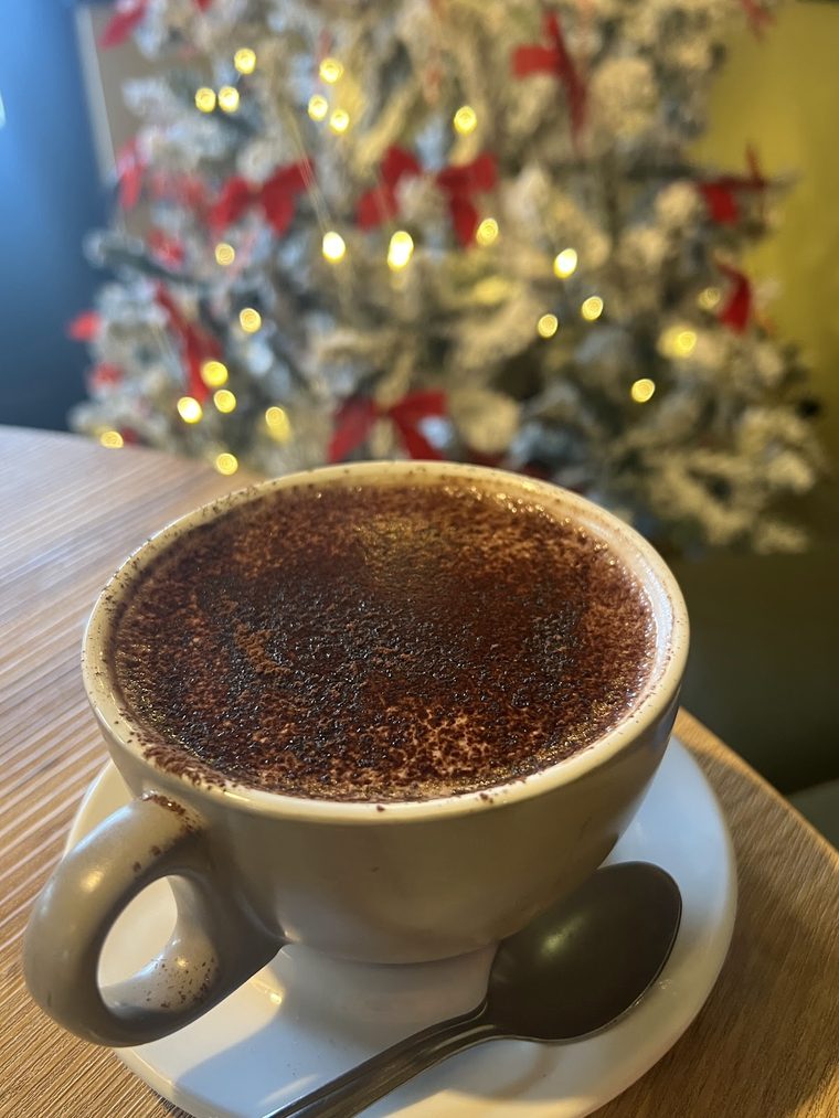 A cappuccino dusted with chocolate in a grey cup and saucer.